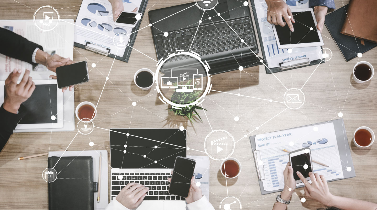 Artisan menuisier dans son atelier consultant une tablette pour la gestion de ses factures, établi avec outils traditionnels en arrière-plan